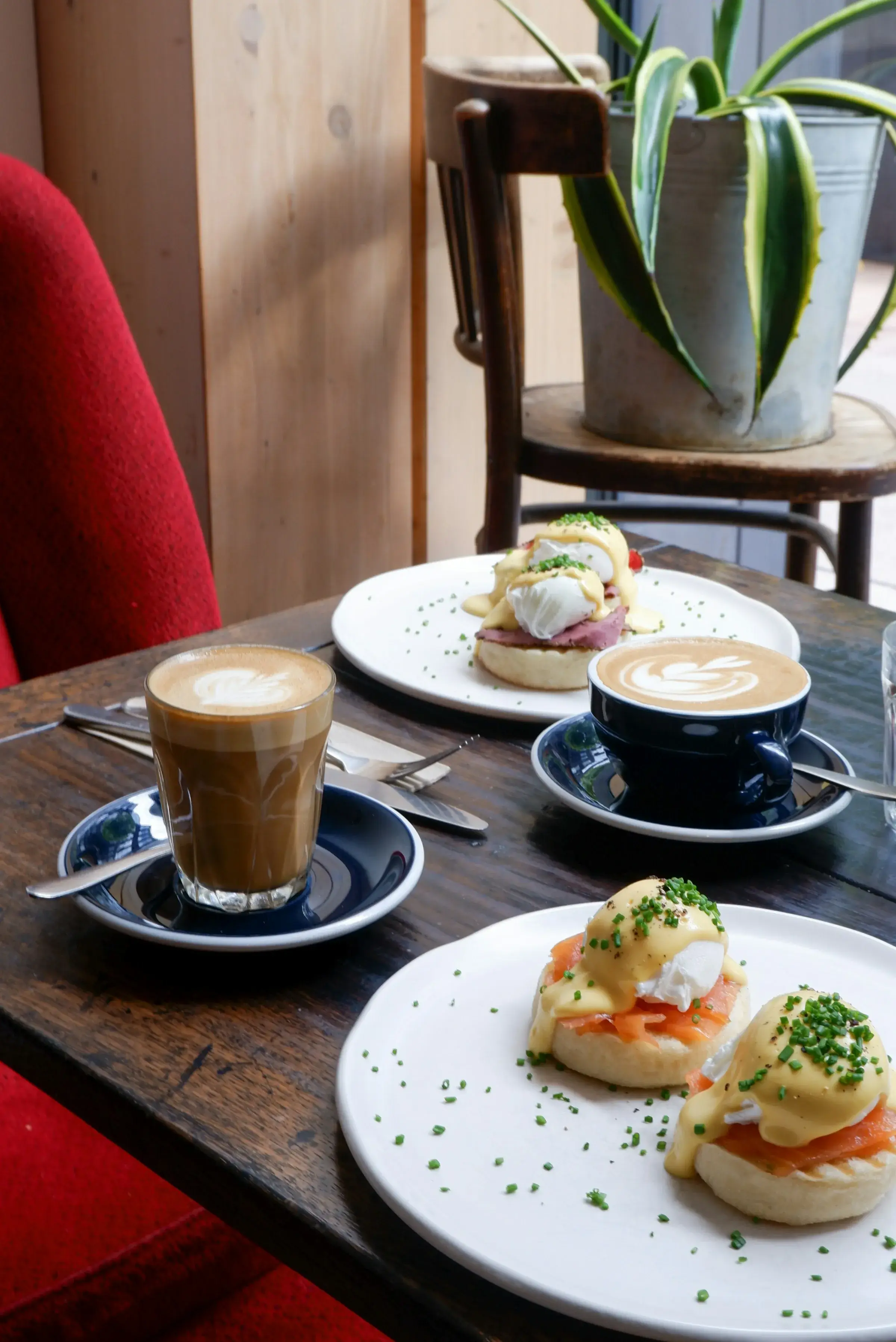 A brunch table with eggs on toast and two coffees in a sunlit café